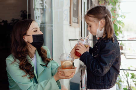 Stock Photo - Mom and little daughter with takeaway drinks in a cafe. Opening a cafe.の写真素材