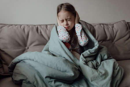 Stop war. Pray for Ukraine. we stand with Ukraine. Ukrainian frightened child under a blanket. The girl is afraid of the sounds of air raids and explosions. Poor child feeling sorrow and sadness.の写真素材