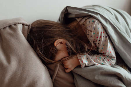 Stop war. Pray for Ukraine. we stand with Ukraine. Ukrainian frightened child under a blanket. The girl is afraid of the sounds of air raids and explosions. Poor child feeling sorrow and sadness.の写真素材