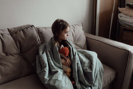 Stop war. Pray for Ukraine. we stand with Ukraine. Ukrainian frightened child under a blanket. The girl is afraid of the sounds of air raids and explosions. Poor child feeling sorrow and sadness.の写真素材