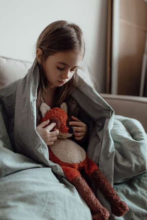 Ukrainian frightened child under a blanket. The girl is afraid of the sounds of air raids and explosions. Poor child feeling sorrow and sadness. Stop war. Pray for Ukraine. we stand with Ukraine.の写真素材