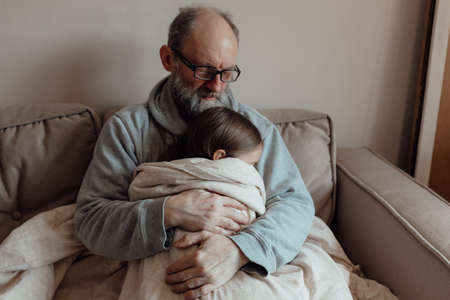 Stop war. Ukrainian worried middle aged hoary man supporting little frightened grandgirl.の写真素材