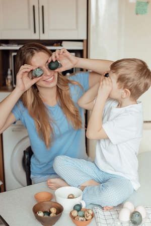 Happy family preparing Easter eggs indoors. Mother and boy celebrating happy Easter holiday together...
