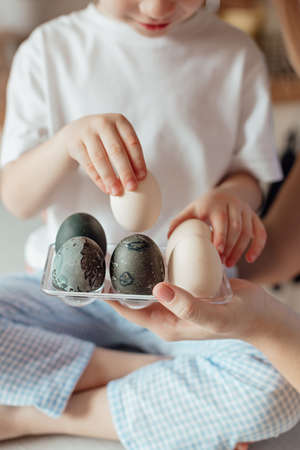 Happy family preparing Easter eggs indoors. Mother and boy celebrating happy Easter holiday together...