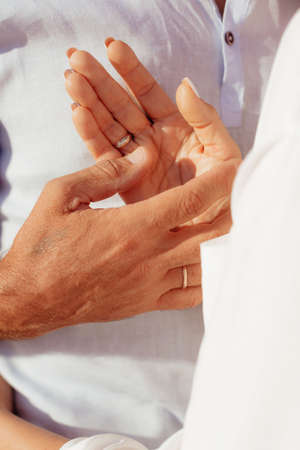 Hands joining together with sunlight flare in the background. Beautiful romantic moment between two lovers. Closeup photo.の写真素材