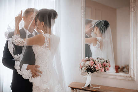 Beautiful young couple, the bride and groom. Luxurious light interior. Wedding day conceptの写真素材