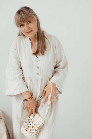 Elderly woman in light clothes on a white background with place for text. Elderly lifestyle at home concept. Mock up for design and banner, clothes shop sale.の写真素材