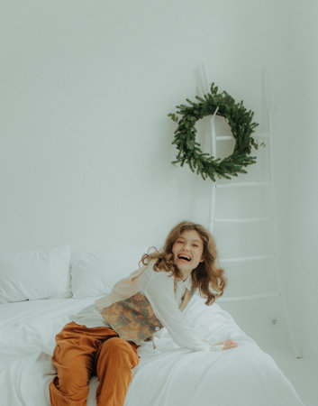 Beautiful festive portrait of a teen girl. Christmas light home background. Waiting for a miracle make a wish under the Christmas tree. Charming smile. New Year's holiday atmosphereの写真素材