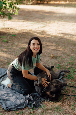 Beautiful happy young woman sitting on the grass hugging a dog. Love and affection for pets,...