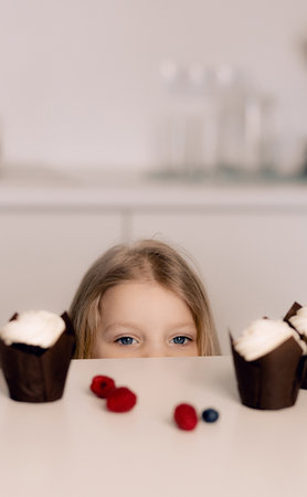Beautiful happy little girl biting birthday cake. Looking at camera. Festive and holiday concept.の写真素材