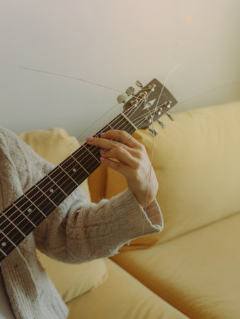 Creative hobby. Female hands with guitar neck, close-up photo. Copy space