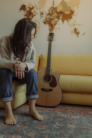 Creative hobby. Talented young female musician sit in armchair alone compose instrumental song using classic guitar. Smiling lady play calm melody on musical instrument. Copy spaceの写真素材