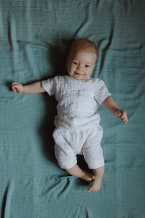 Top view wide angle newborn baby lies in a crib arms. A newborn baby is resting in bed. Nursery for small children. Textiles and bed linen for children. Family morning at home.の写真素材
