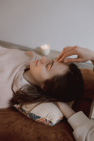 Female energy massage relaxing and care treatment for body and mindfull health gentle woman arms holding head doing access bars and face young procedure. Energetic massage resumes the circulation of energy in body.の写真素材