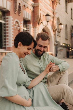 Pregnant couple walks around the city. Husband with his pregnant wife walking on the background of the city and the park. Happy family concept photo. No focus blurred and noise effectの写真素材