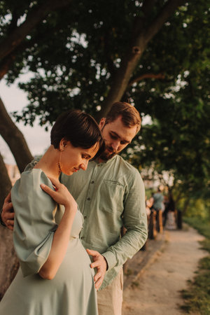 Pregnant couple hugging in nature. Husband with his pregnant wife walking in park. Happy family concept photo. No focus blurred and noise effectの写真素材