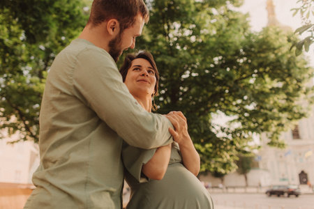 Pregnant couple hugging in nature. Husband with his pregnant wife walking in park. Happy family concept photo. No focus blurred and noise effectの写真素材