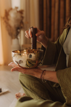 Woman playing on Tibetan singing bowl while sitting on yoga mat. Vintage tonned. Soft focus blurred and noise effect.の写真素材