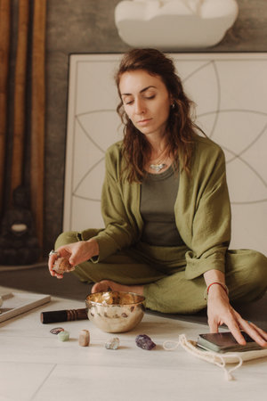 Woman playing on Tibetan singing bowl while sitting on yoga mat. Vintage tonned. Soft focus blurred and noise effect.の写真素材