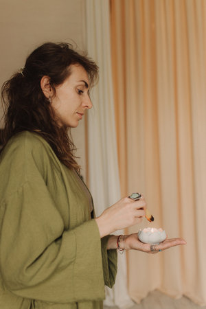 A young woman holds a smoking palo santo stick in her hands. Buddhist healing practices.Clearing the space of negative energy. Aromatherapy. Selective focus,close up. Soft focus and noise effect.の写真素材