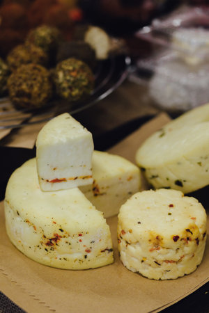 hand made baked stuffed rolls and pieces of cheese. Delicious pastries on wooden cutting board and parchment paper at the street food fair. Soft focus blurred and noise effect.の写真素材