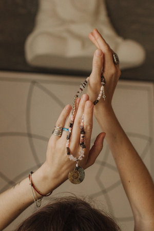 Woman holds jewelry made of natural stones in her hand, her hands are decorated with rings and...