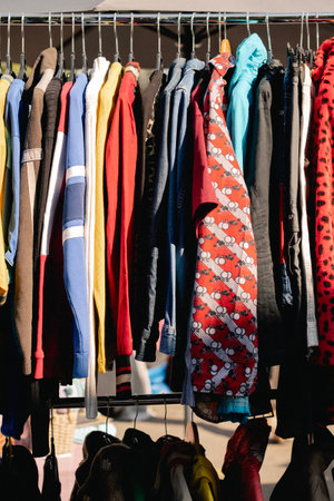 Choice of fashion clothes of different colors on hangers in a retail shop. Flea market with old clothes outside. Reduce Reuse Recycle concept.の写真素材