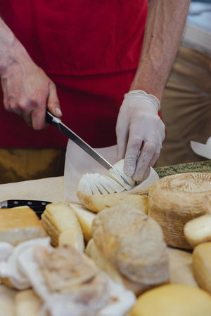 Cheesemaker cuts cheese. Pieces of cheese on a wooden board with cook hands and a knife. Cutting cheese, slicing cheese. close-up.の写真素材