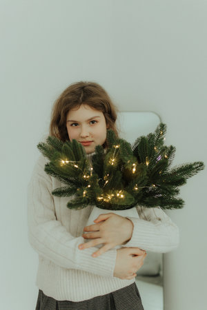 A joyful smiling young woman is preparing for the Christmas holiday and decorating a Christmas tree...