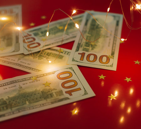 Background for holiday card with money US dollars. Background of one hundred dollar bills. Banknotes, paper currency on red background. Concept of american and global economy, exchange rate, xmas.の写真素材