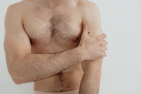 People, healthcare and problem concept - man suffering from pain or reins. Close up hands touching pain. Man standing on white background. No focus blurred and noise effect.の写真素材