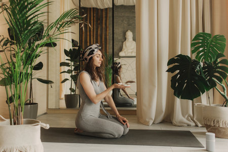A young woman lighting incense sticks an home before yoga. Buddhist healing practices. Clearing the space of negative energy. Aromatherapy. Selective focus.の写真素材