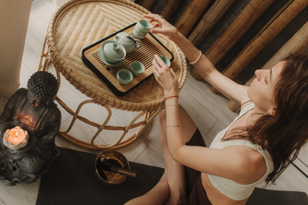 Young woman is pouring hot tea a tea ceremony. Woman hands holding cups. Wooden table with...