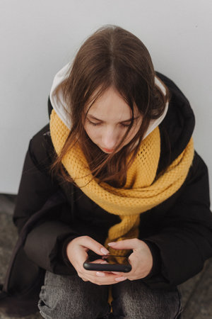 Half length portrait of girl in casual wear holding smartphone for blogging in the city in the...