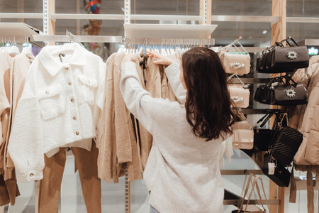 Korean teenage girl choosing and buying trendy clothes in a shopping mall. Retail and consumerism. Sale promotion and shopping concept. Part of a series.の写真素材