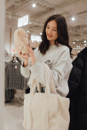 Korean teenage girl choosing and buying trendy clothes in a shopping mall. Retail and consumerism. Sale promotion and shopping concept. Part of a series.の写真素材