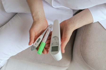 Close-up female gp physician doctor holding different types of thermometers for measuring human body...
