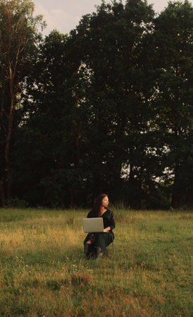 Woman using laptop in IT outside in eco-farm. Online chat. Spend free time on nature. Concept working from home, slow life, staying connected, social distancing, internet. Part of the series.の写真素材