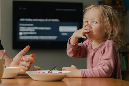 Close up baby girl looks at a plate with a sandwich. The parent's hand offers food to the child to choose from. Children and healthy eating concept. Part of the seriesの写真素材