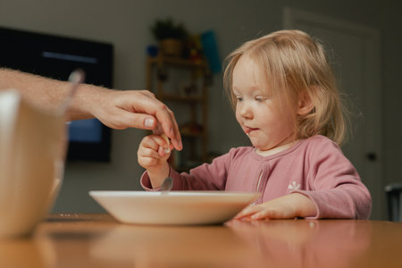 Close up baby girl looks at a plate with a sandwich. The parent's hand offers food to the child to choose from. Children and healthy eating concept. Part of the seriesの写真素材