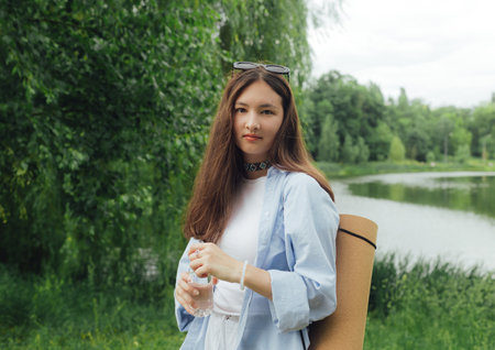 Korean girl with yoga mat for practicing yoga looking for a place to meditate in the park. Unity...