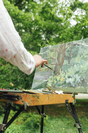 Close up of female artist's hands make a brush stroke on the canvas. Mindfulness, art therapy,...