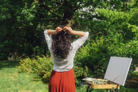 Female artis paints a picture in the park. Mindfulness, art therapy, creativity concept. Process of plein air painting in nature. A series of photos showing the step-by-step creation of a painting.の写真素材