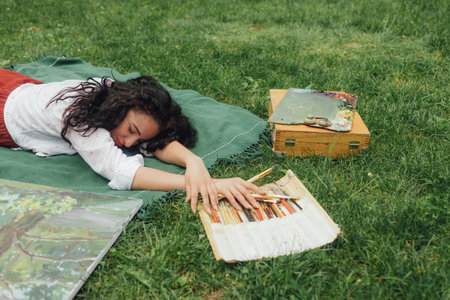 Female artis paints a picture in the park. Mindfulness, art therapy, creativity concept. Process of plein air painting in nature. A series of photos showing the step-by-step creation of a painting.の写真素材