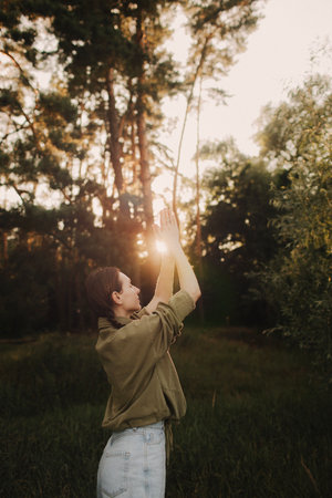 Unity with nature and wellness concept. Overjoyed woman enjoying with a yoga mat for yoga practice meditates in the park. Concept of female people and healthy natural lifestyle. Part of the series.の写真素材