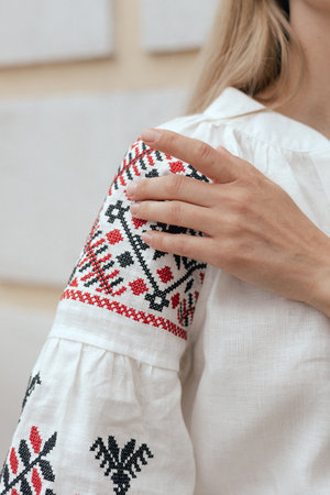 Close-up of female hands in shirt with red and black thread, space for text. Ukrainian national...