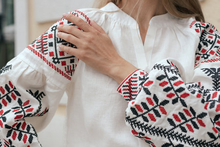 Close-up of female hands in shirt with red and black thread, space for text. Ukrainian national...