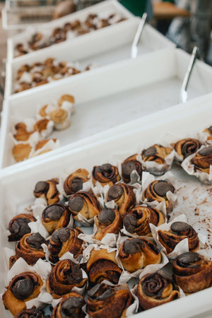 Cinnamon rolls or Cinnabon, homemade sweet traditional dessert buns with white cream sauce on white...