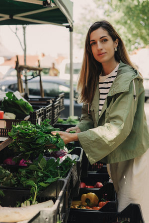 Woman on the market. Mature Female Customer Shopping At Farmers Market Stall. Woman shopping at the local Farmers market. Beautiful woman buying vegetables. Close up. Part of the series.の写真素材