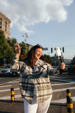 Vlogger traveler woman recording video on phone camera on Khreshchatyk in Kyiv, Ukraine. Gen Z Plus size girl influencer shooting social media stories on the street. Part of a series. UGCの写真素材